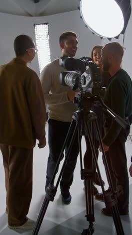 Vertical-Video-Of-Film-Crew-And-Female-Director-Congratulating-Actors-After-Performance-Shooting-Movie-In-Studio-Shot-In-Real-Time